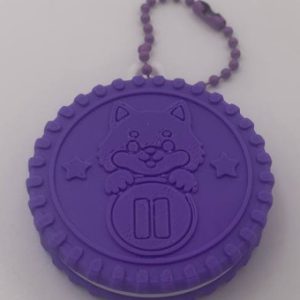 Vista frontal de la Cookie Madrid 2026 morada impresa en 3D con perrito en relieve y cadena de llavero